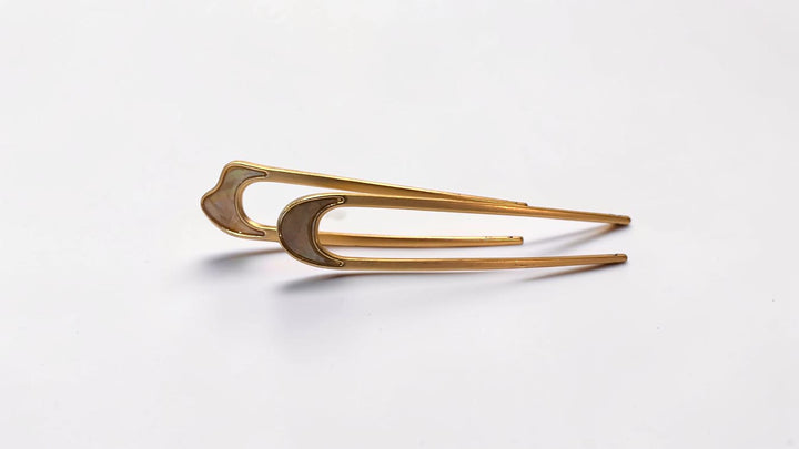 Side view of two gold-tone French hair pins with iridescent crescent accents