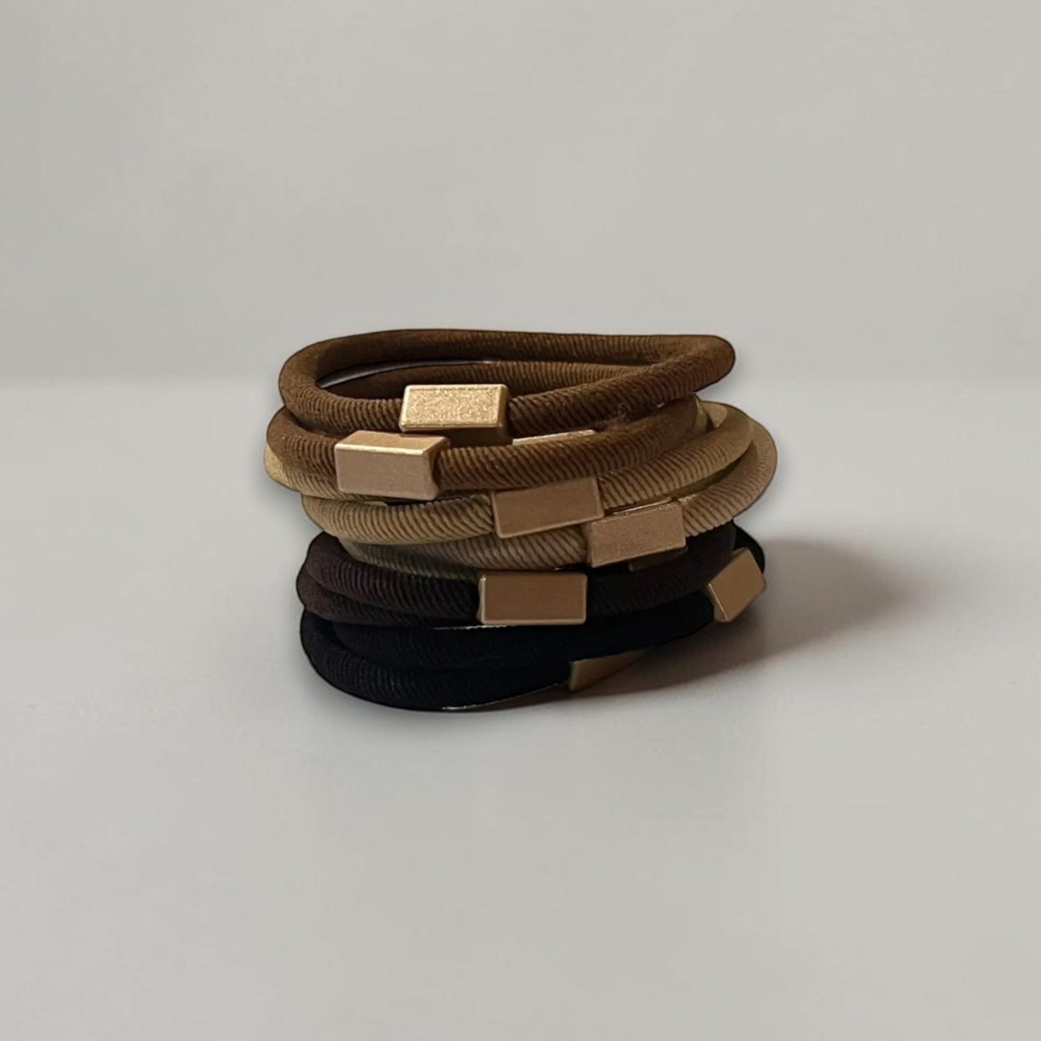 Stacked neutral hair ties with gold-tone accents